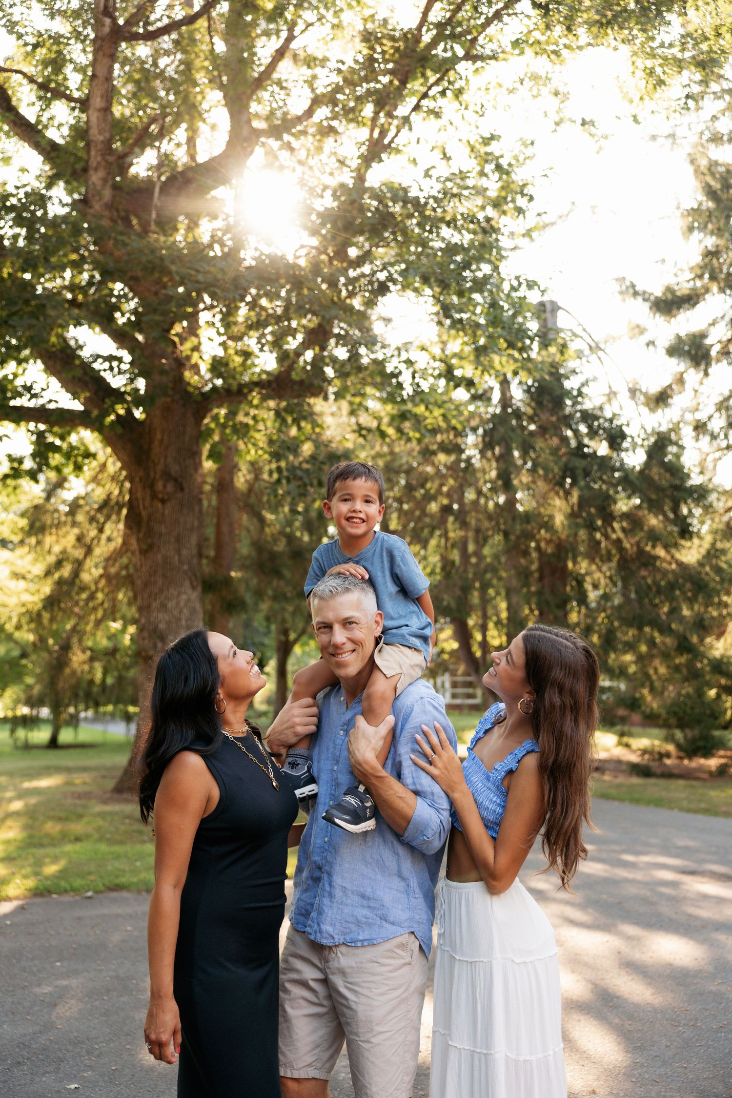A cheerful family gathering outdoors under sunlit trees on a warm summer day.