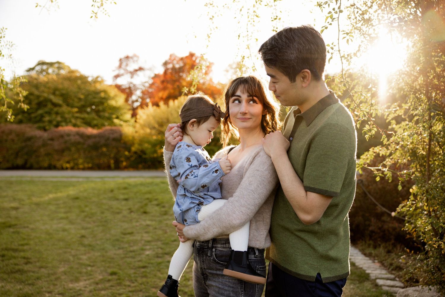 Family embraces in warm sunset light during outdoor autumn photo session.