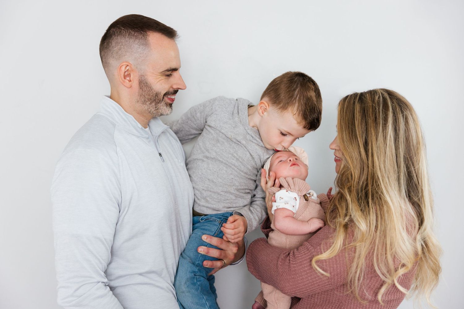 Candid family photography session showing joyful moments in white studio setting.