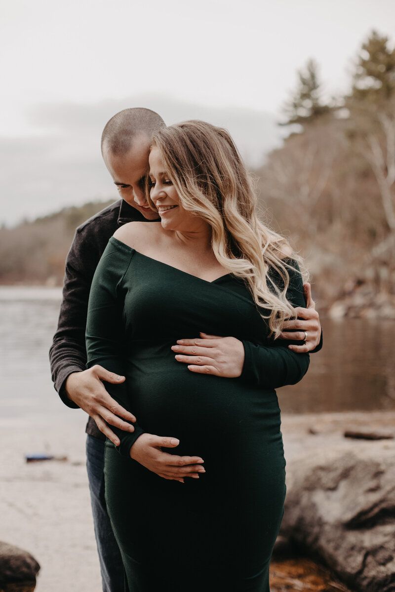 Maternity photoshoot by a lake featuring intimate moments and natural scenery.