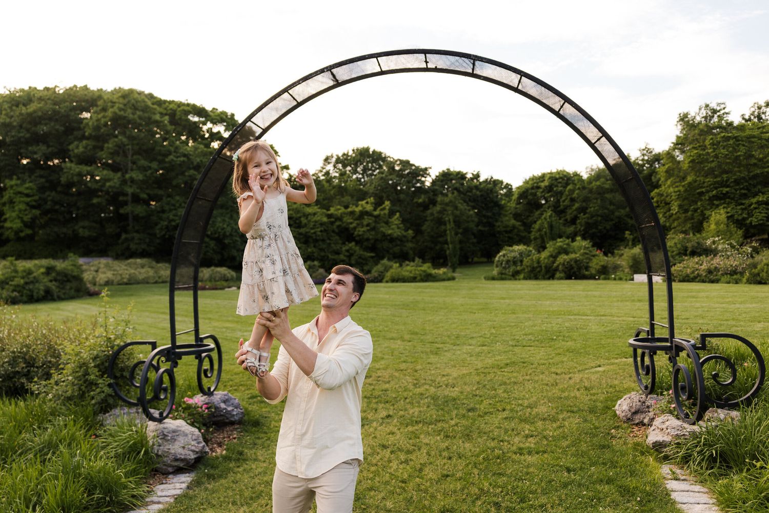 Natural family moments captured under a garden arch surrounded by greenery.