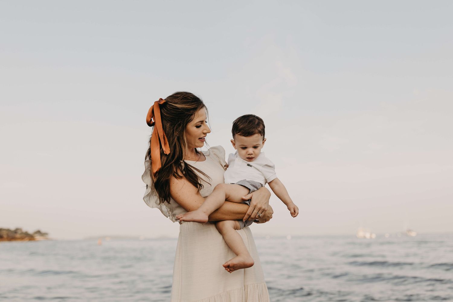 Family embraces on rocky beach during golden hour sunset photography session.