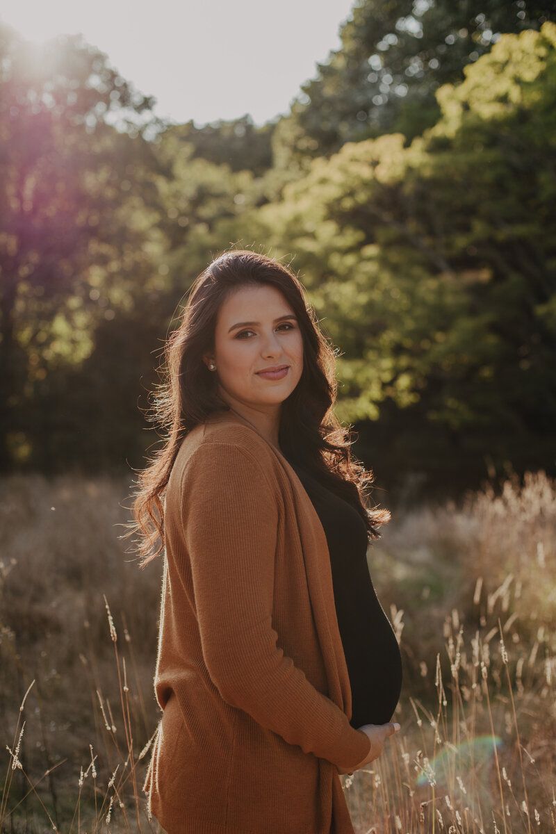 Golden hour portrait session in a field of tall grass with warm autumn lighting and natural scenery.