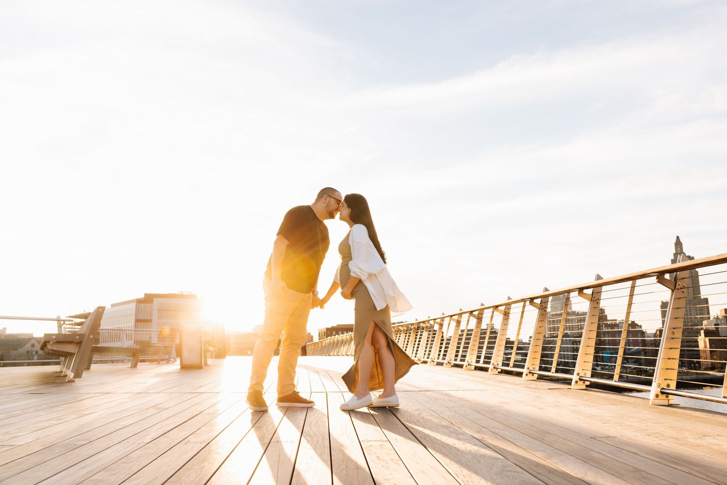 Romantic sunset photoshoot on waterfront pier with golden light.