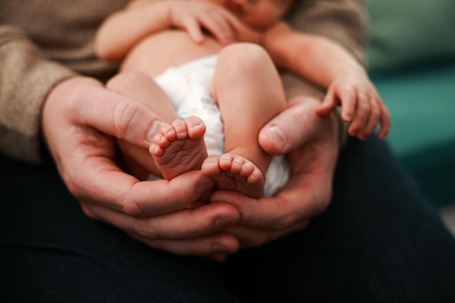 Close-up of tiny baby feet being held in adult hands.