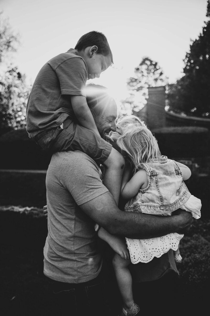 Black and white candid family moment captured during sunset photoshoot.