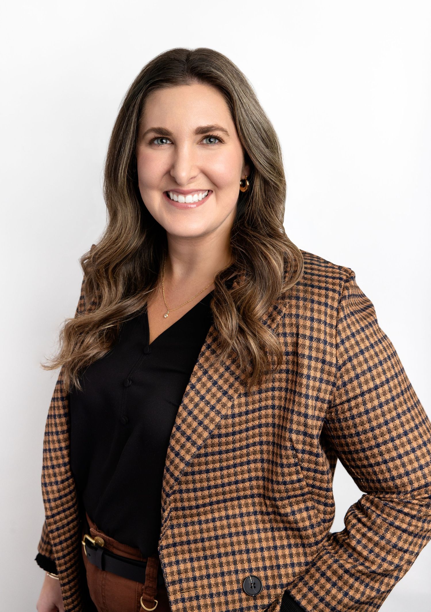 Professional woman smiling in a plaid blazer and black top against a white background.