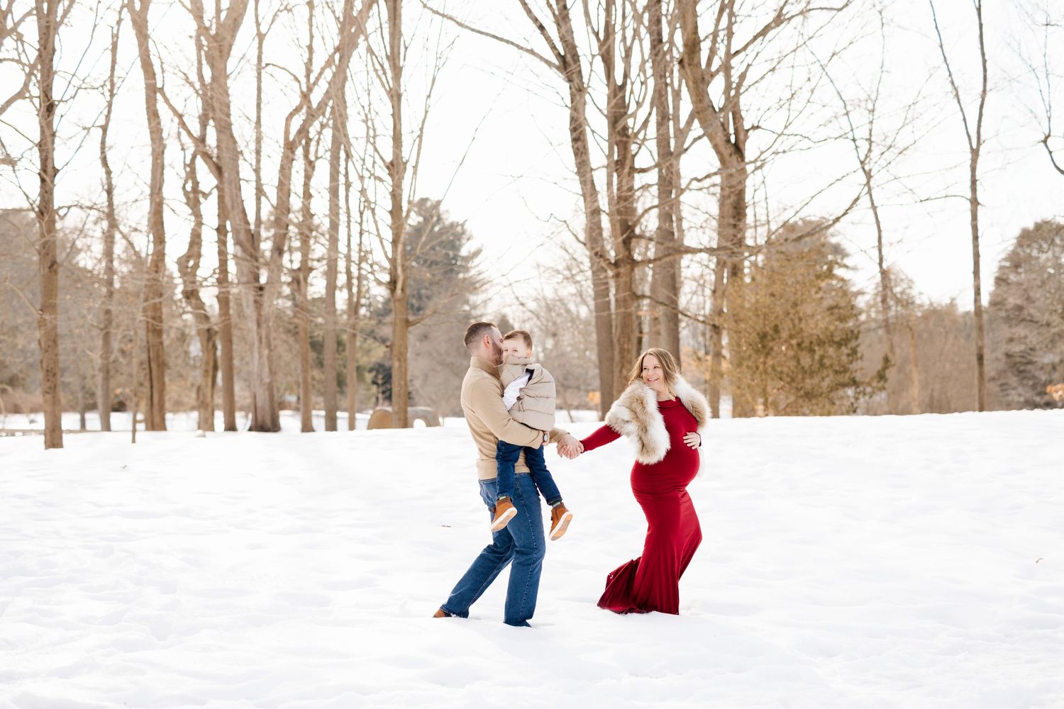 A couple playfully throws snowballs at each other during winter in a snow-covered wooded area.