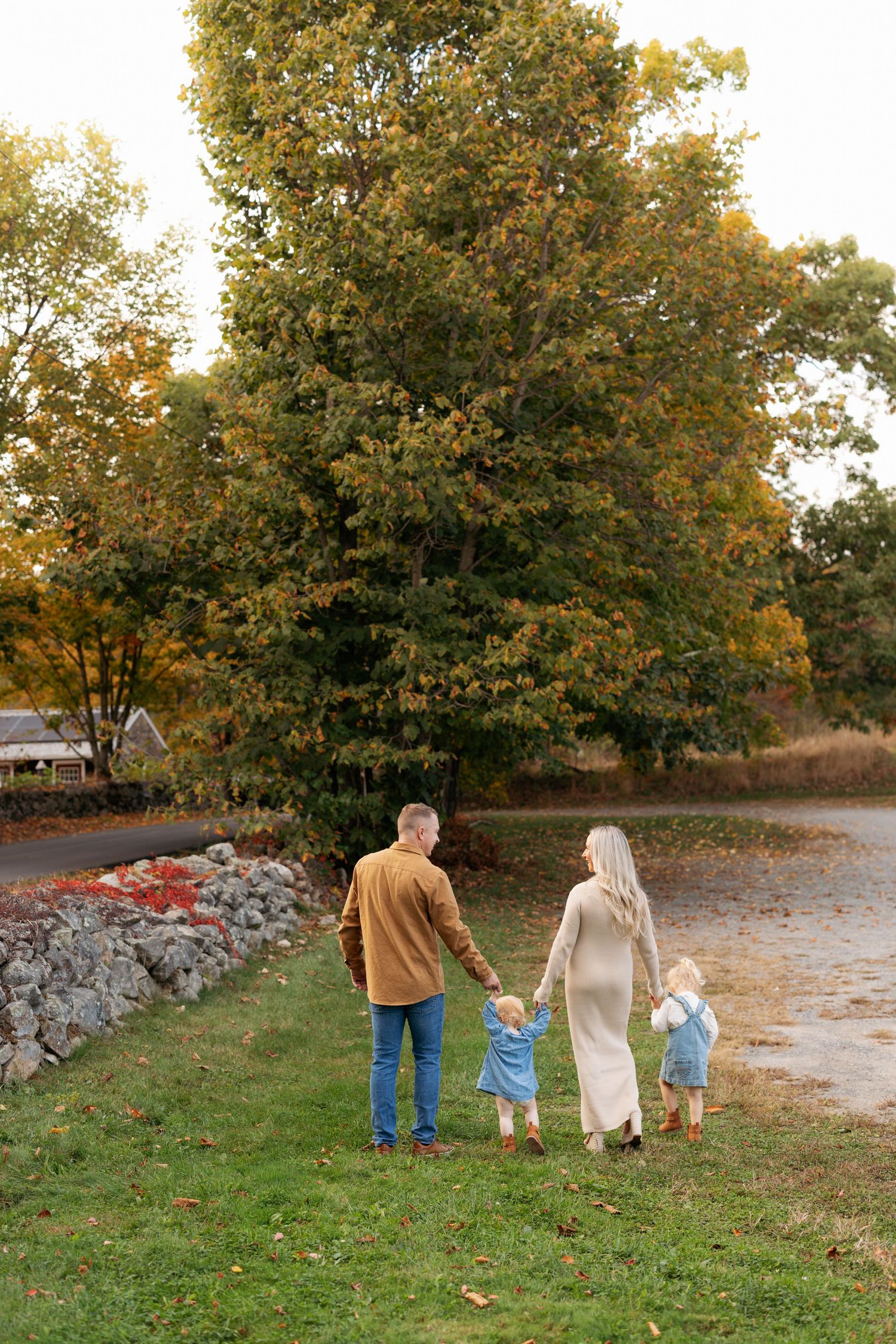 A group walks together along a stone wall during sunset in autumn.