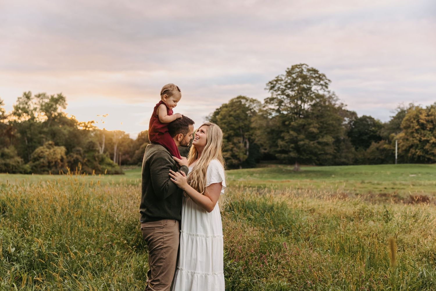 Couple sharing romantic moments in a sunlit meadow at sunset.