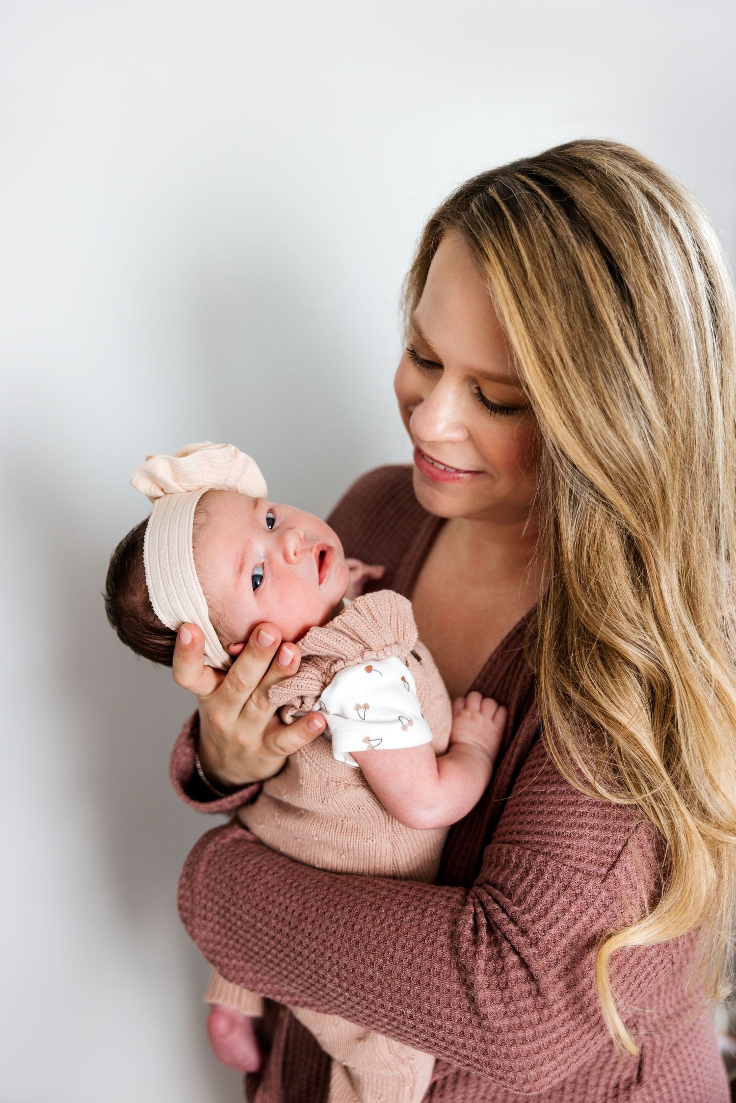 Lifestyle newborn session with soft natural lighting and mauve knit sweater.