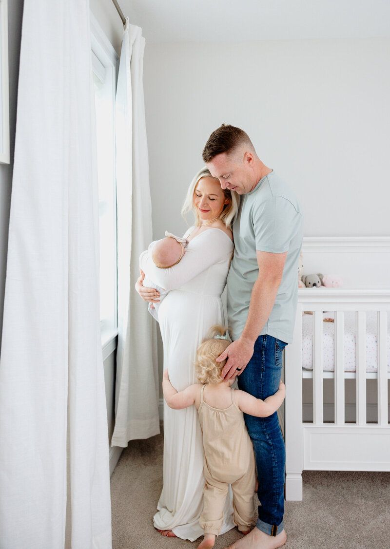 Intimate family photos in minimalist nursery with white decor.