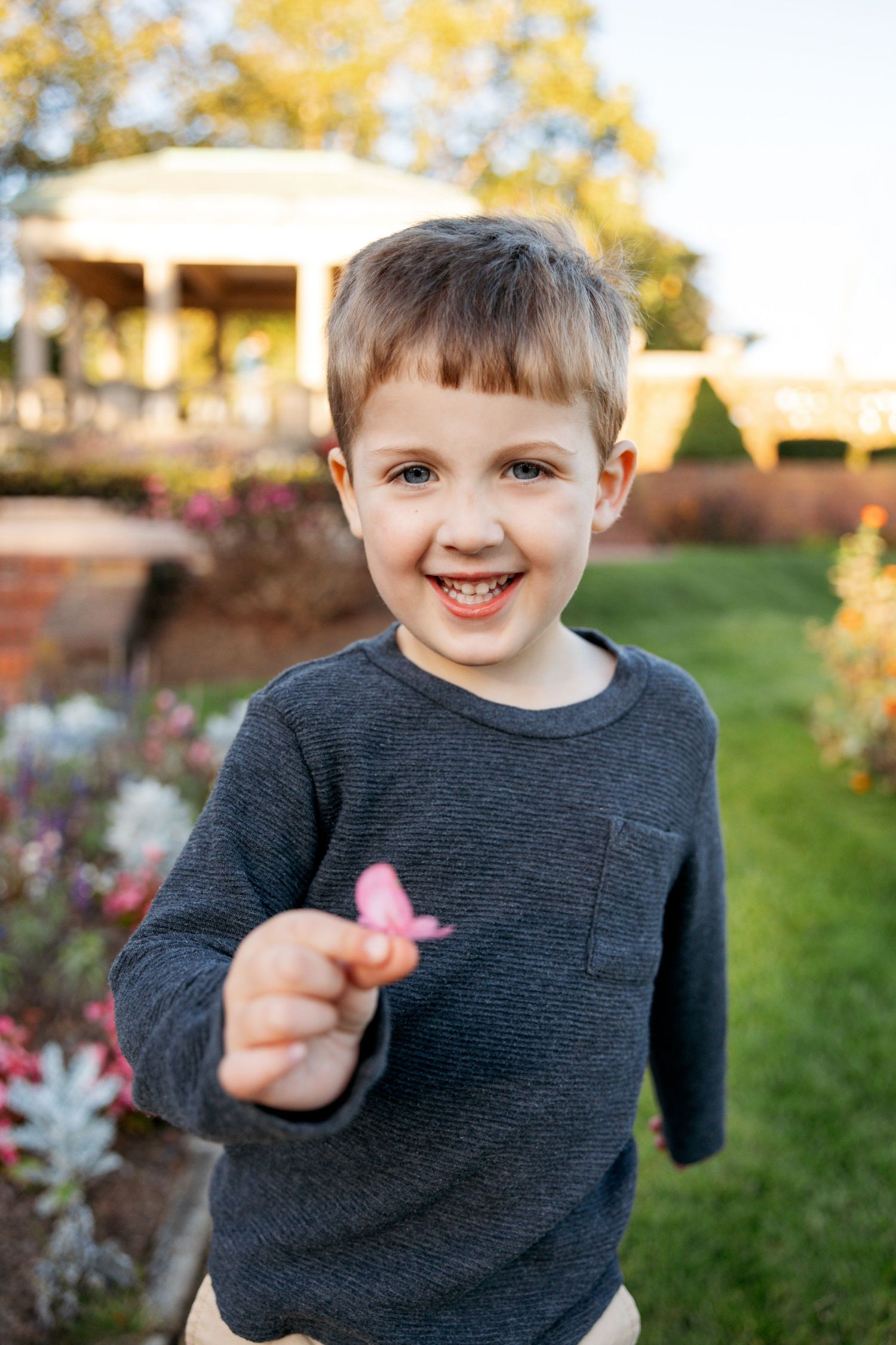 Close-up portrait of a child in a dark grey sweater smiling and playing outdoors on an autumn day.