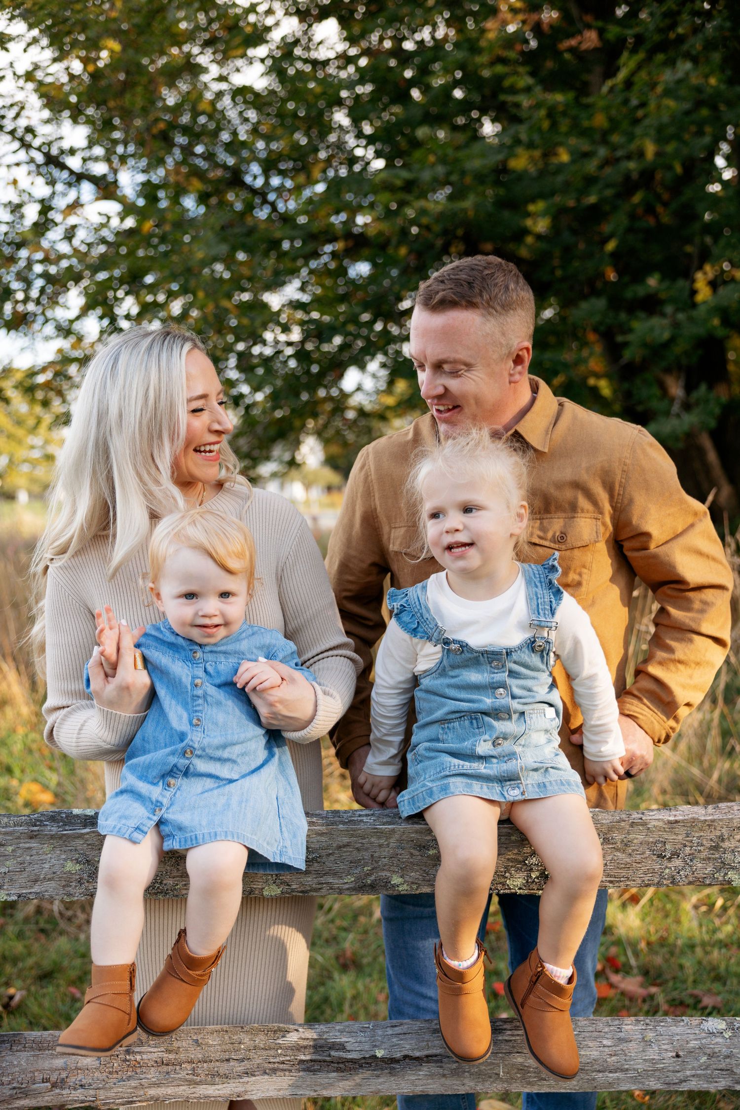 A playful family moment captured on a fallen tree log in an autumn outdoor setting.