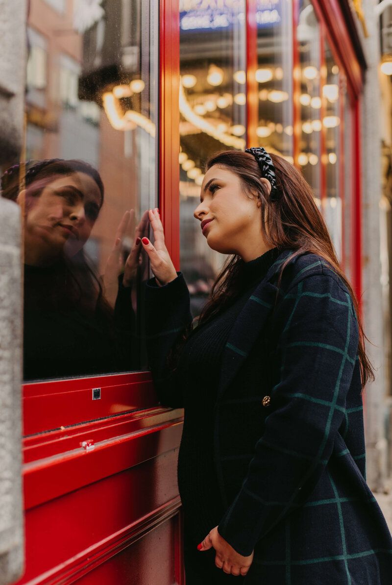 Artistic portrait series with reflections in red-framed window.
