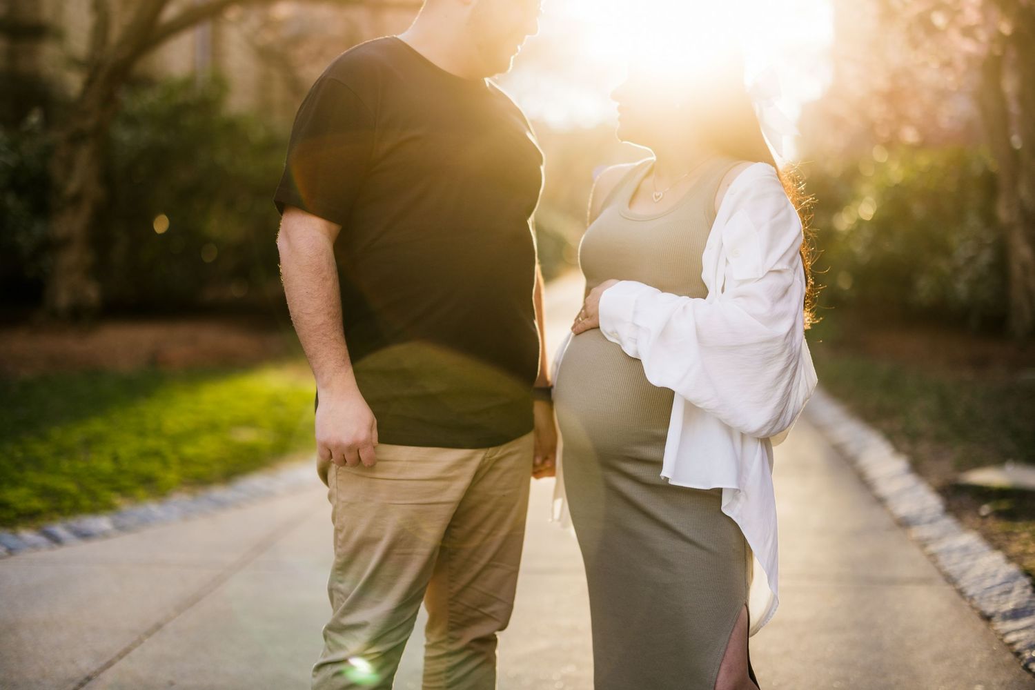 Expectant couple walking together during golden hour photo session.