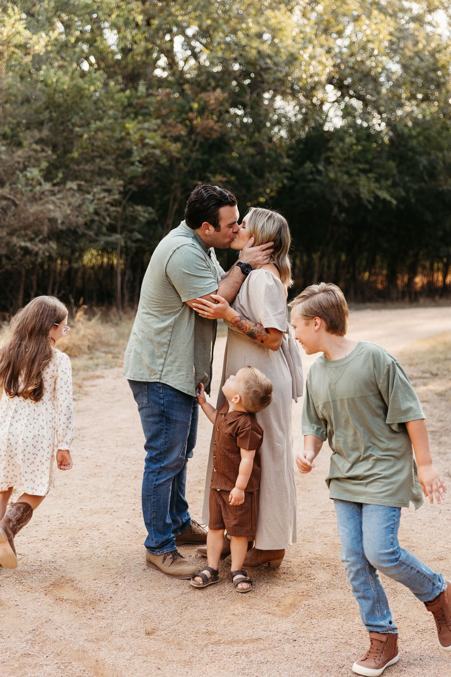 Family enjoying a tender moment together on a dirt path surrounded by autumn trees in warm natural lighting in San Antonio
