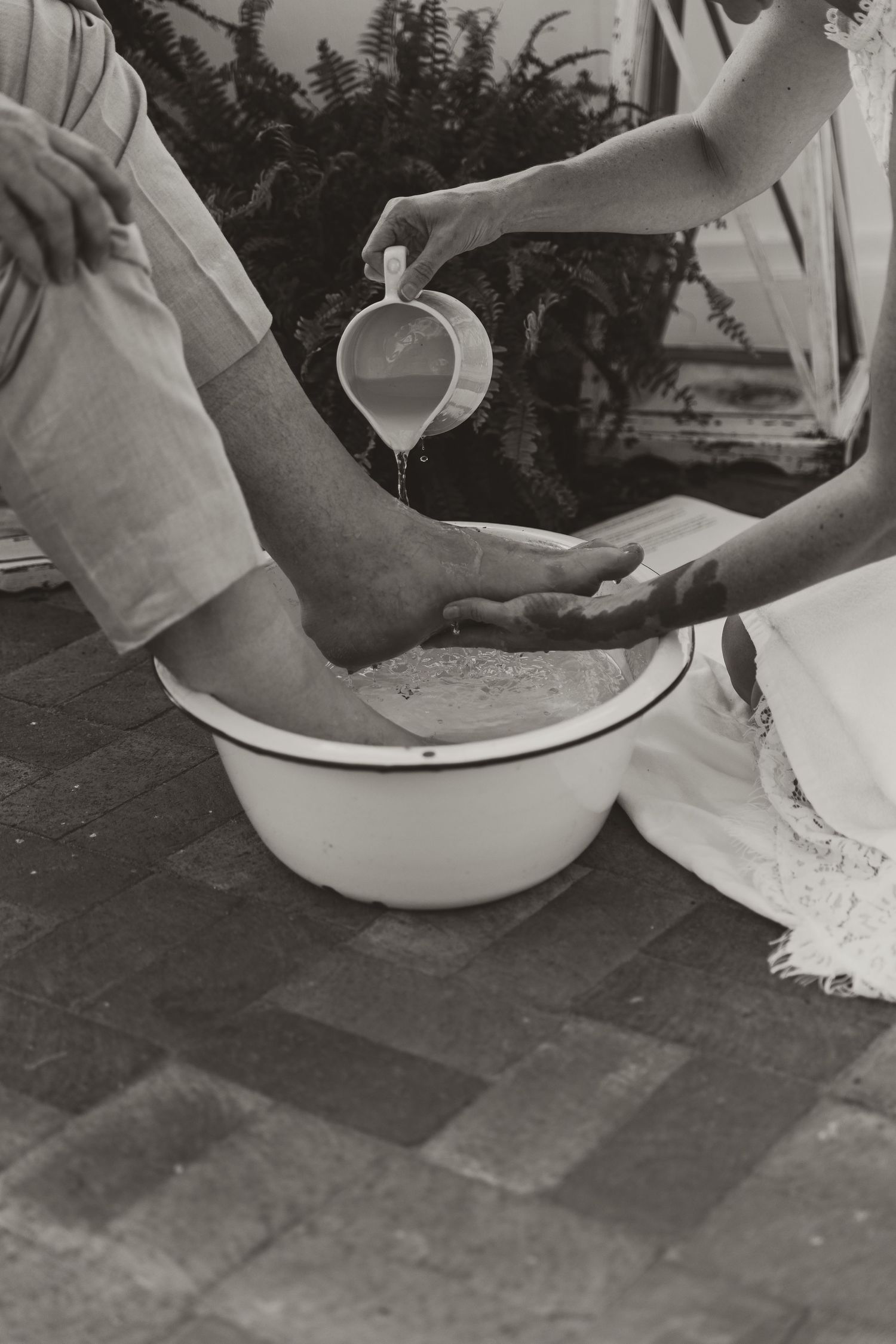 Black and white photo showing a couple washing feet during their wedding