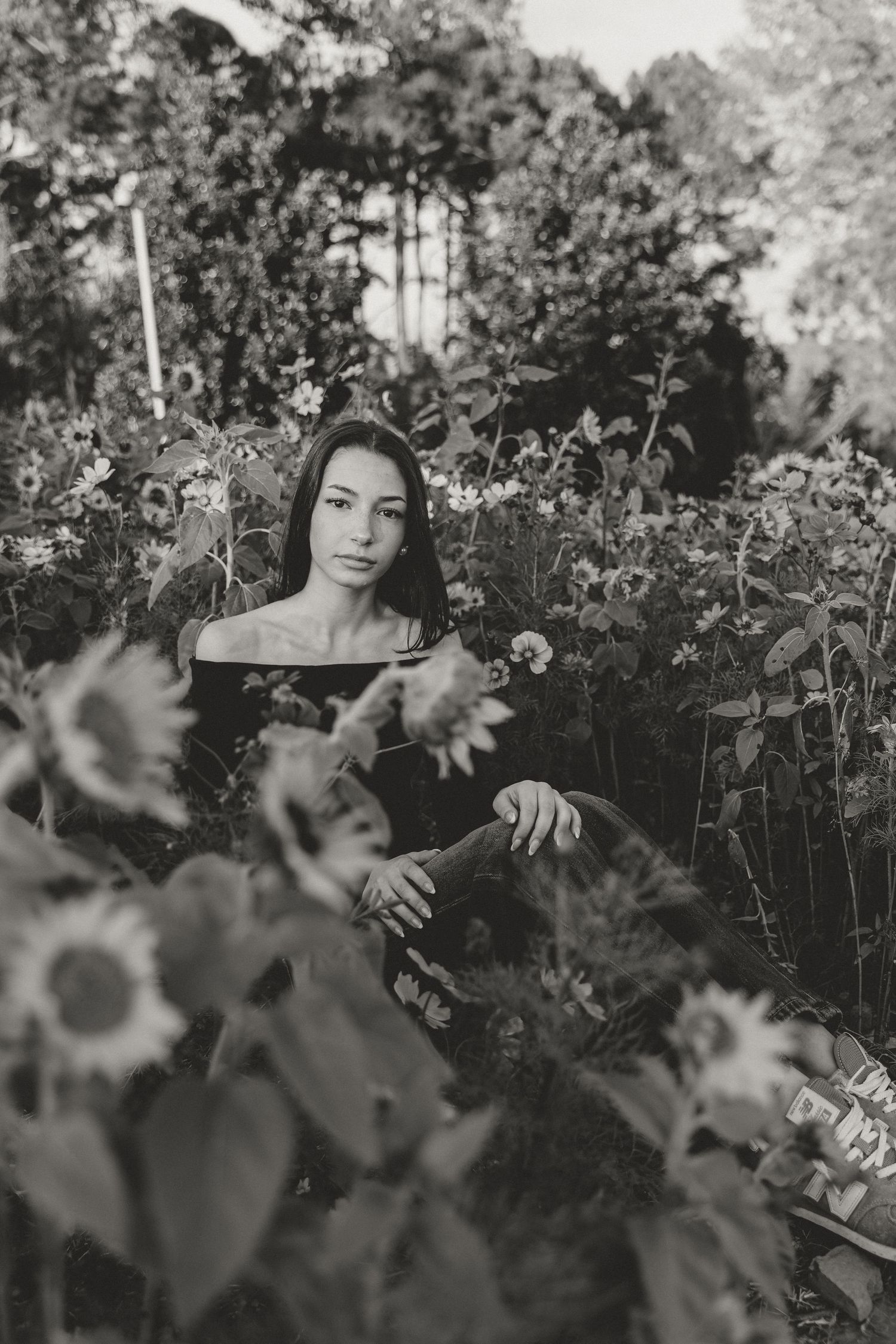 Artistic black and white photo series showing a person posing among tall sunflowers in a garden setting.
