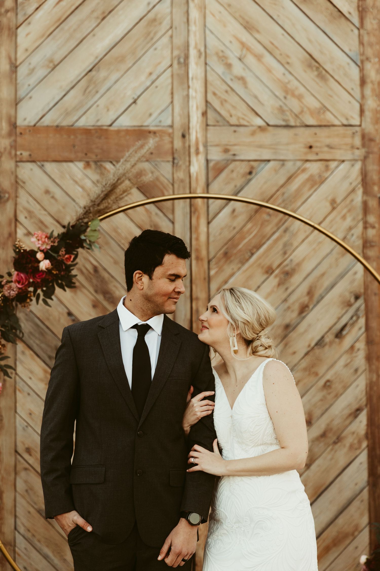 photos show a couple in formal attire posing against a rustic wooden barn door background.