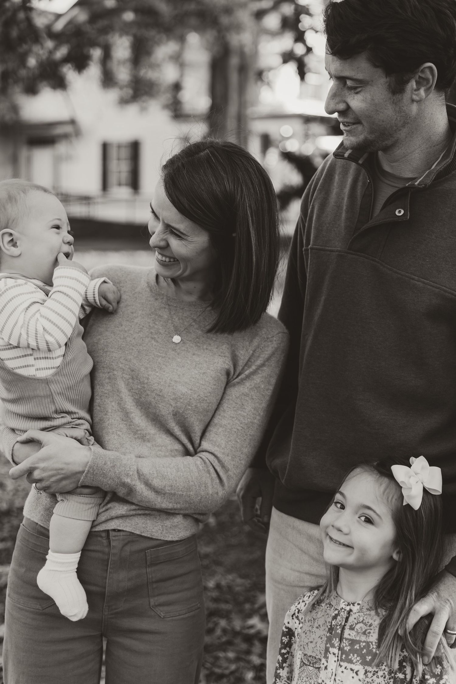 A black and white photo series showing tender family moments between parents and a young child outdoors.
