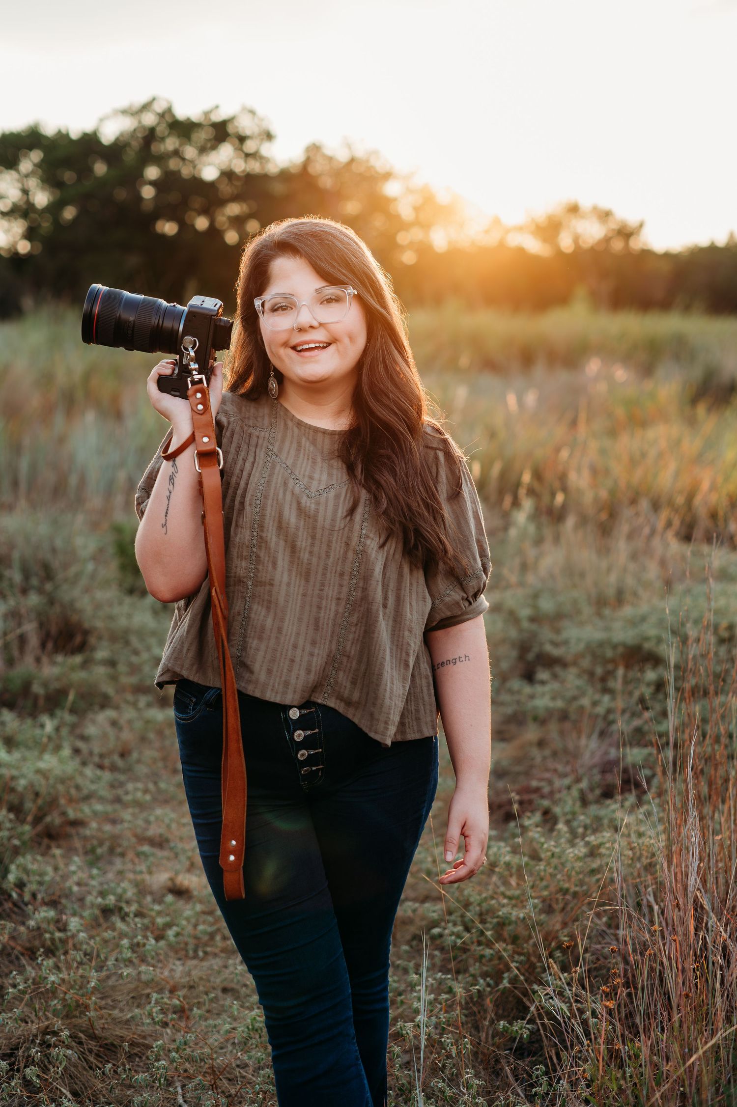 Kori Frazier Photography in San Antonio with her camera at Phil Hardberger park looking at camera and smiling