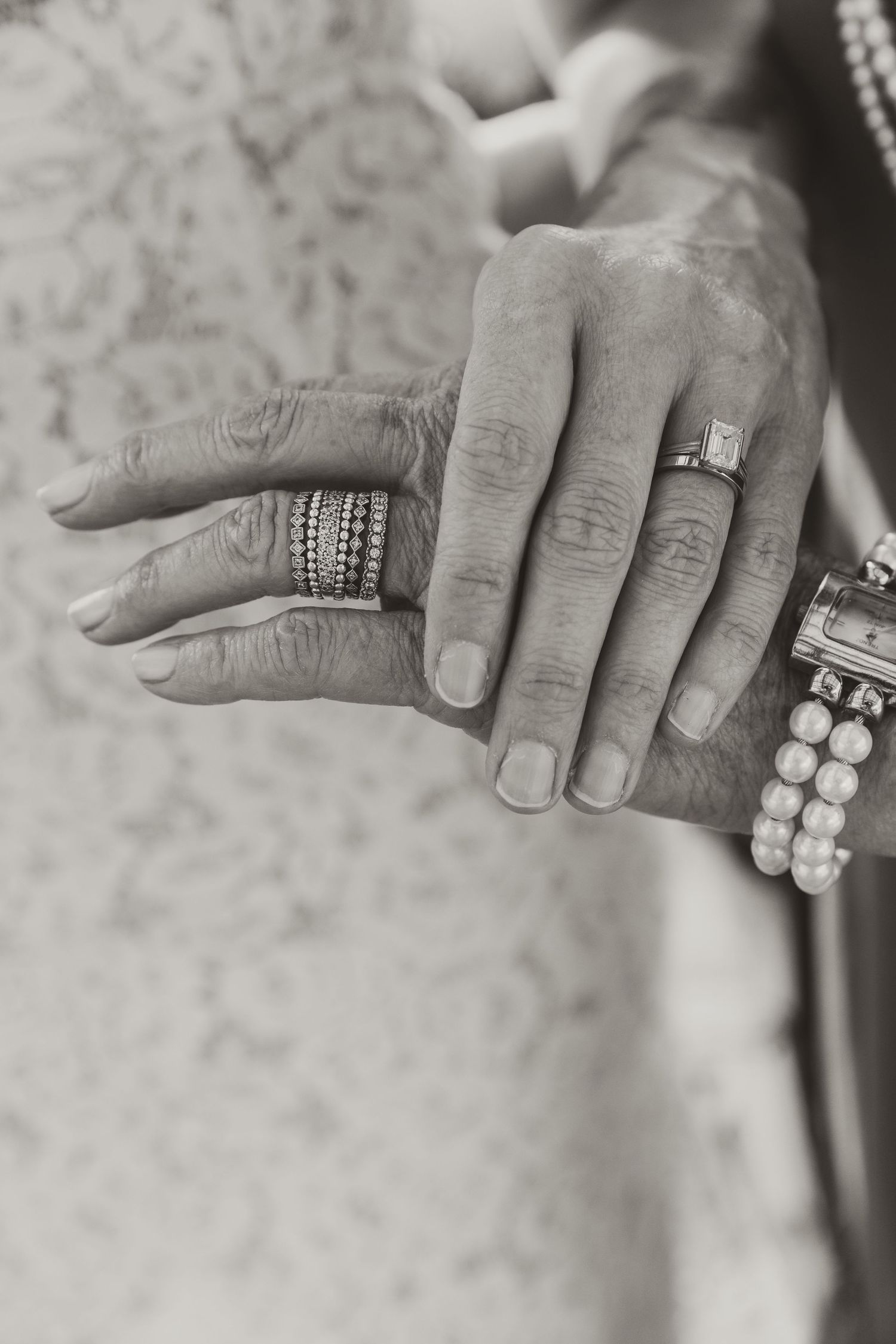 A series of black and white photographs showing hands wearing elegant rings and bracelets against a textured background.