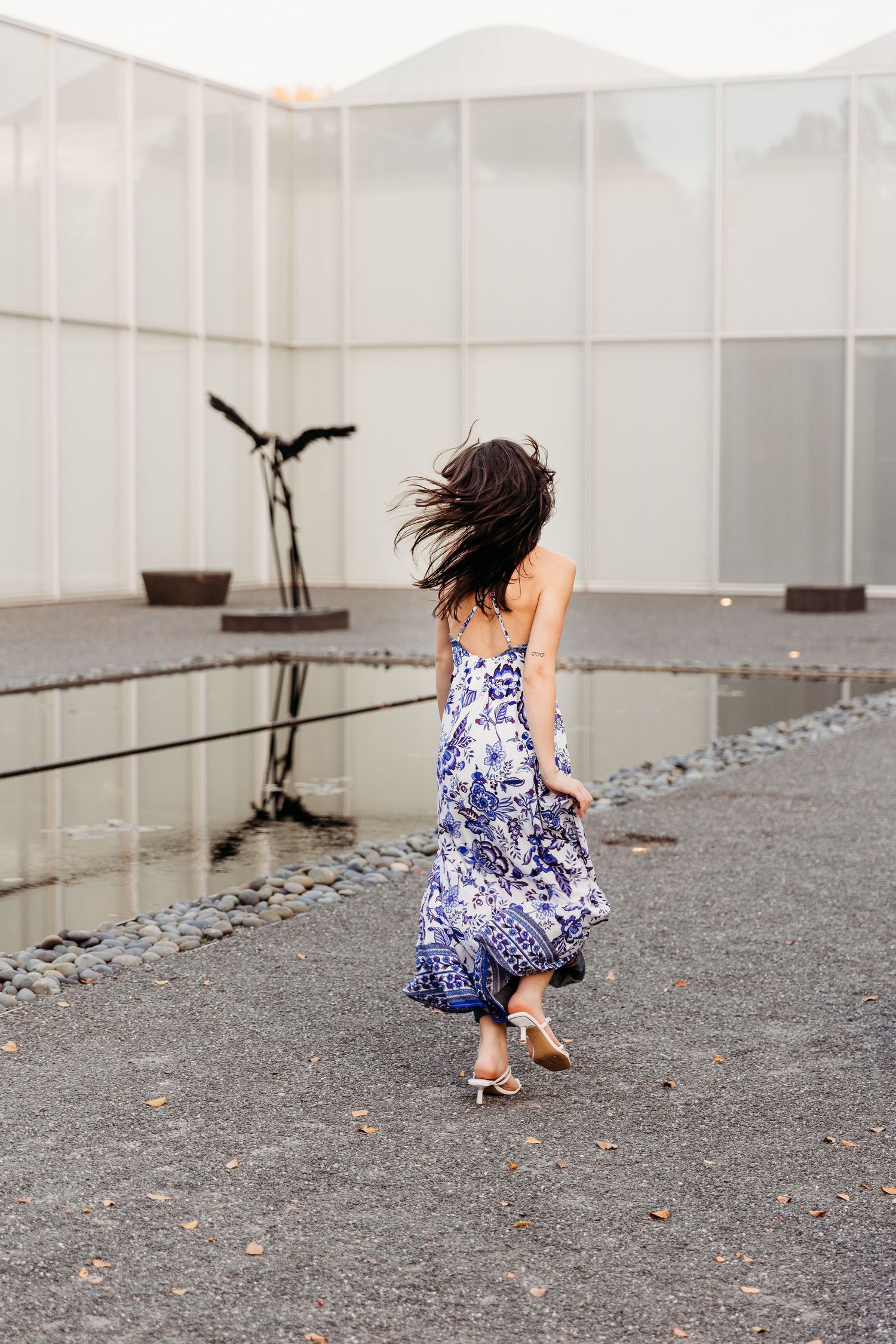 Woman in blue floral running on gravel surface in artistic photo showing fluid movement.