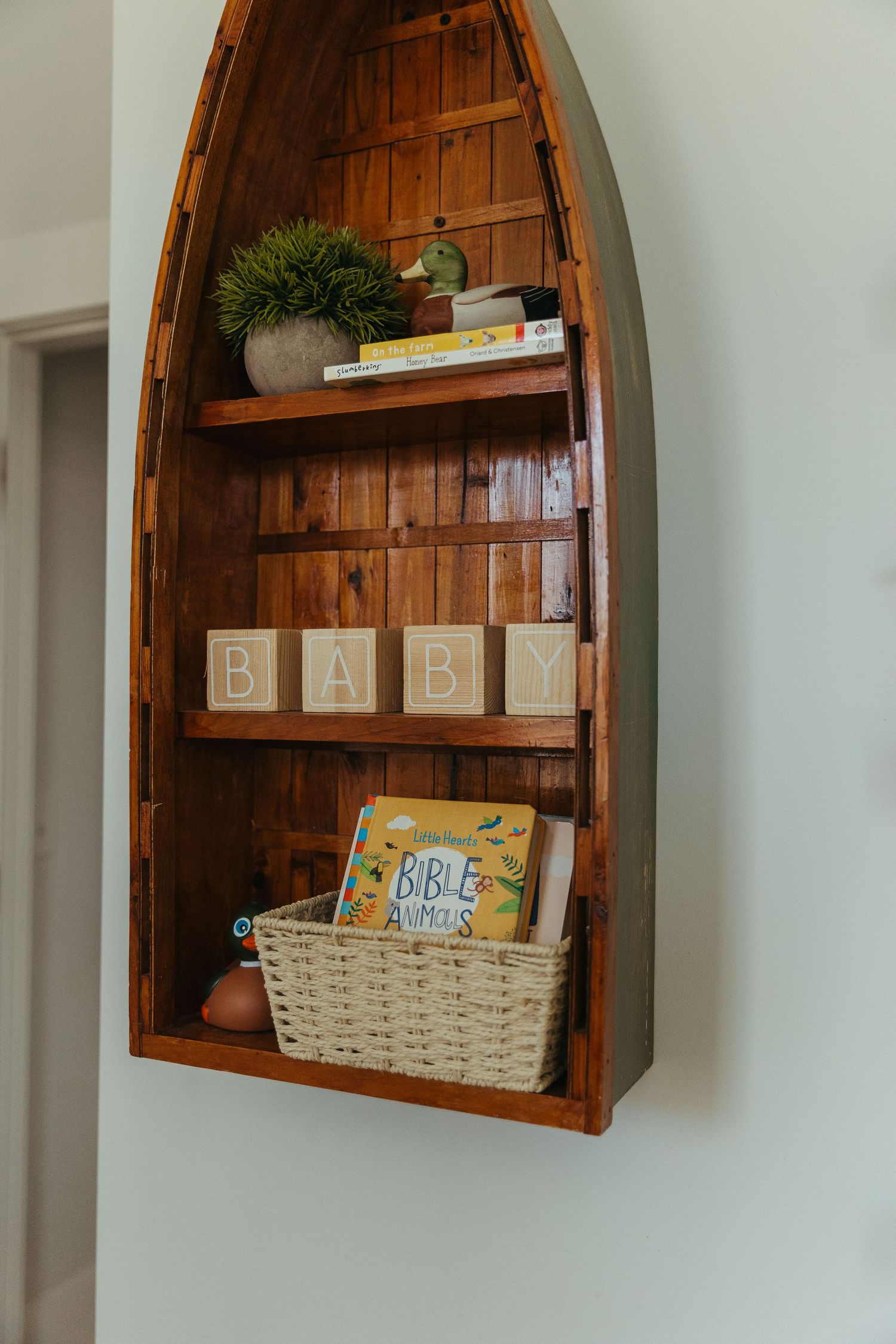 Rustic wooden boat-shaped wall shelves displaying decorative baskets and books in a coastal-inspired home decor arrangement.