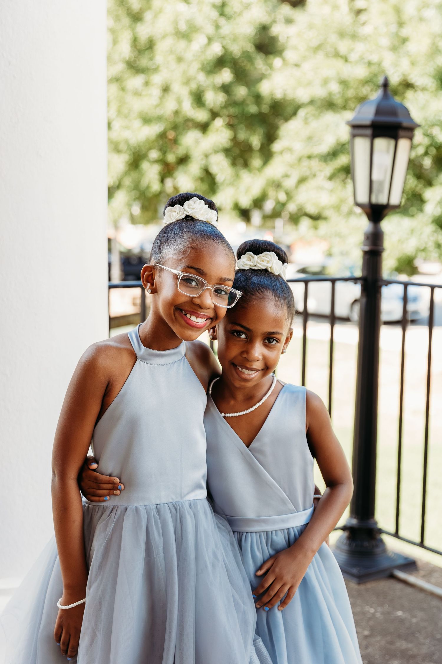 Two people in matching light blue dresses share a joyful moment together outdoors.