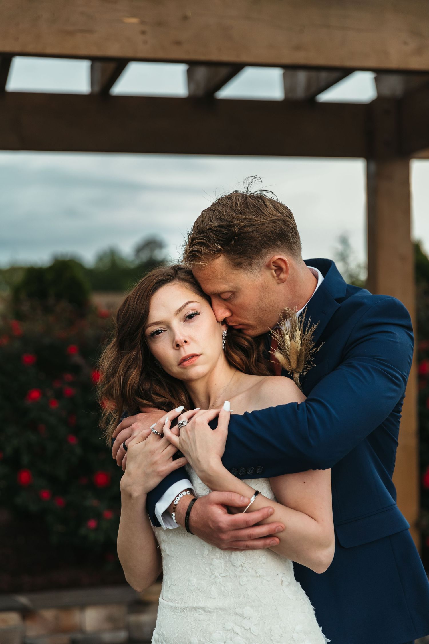 Romantic close-up portrait of couple embracing outdoors with hands clasped showing engagement ring.
