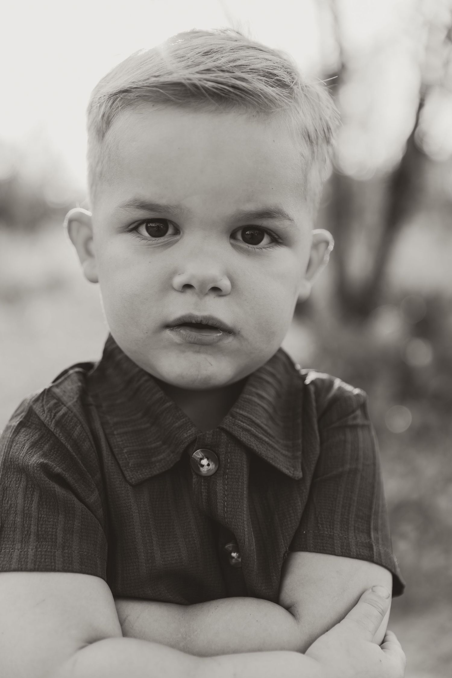 A black and white photo series showing a young child in a dark button-up shirt making different facial expressions.