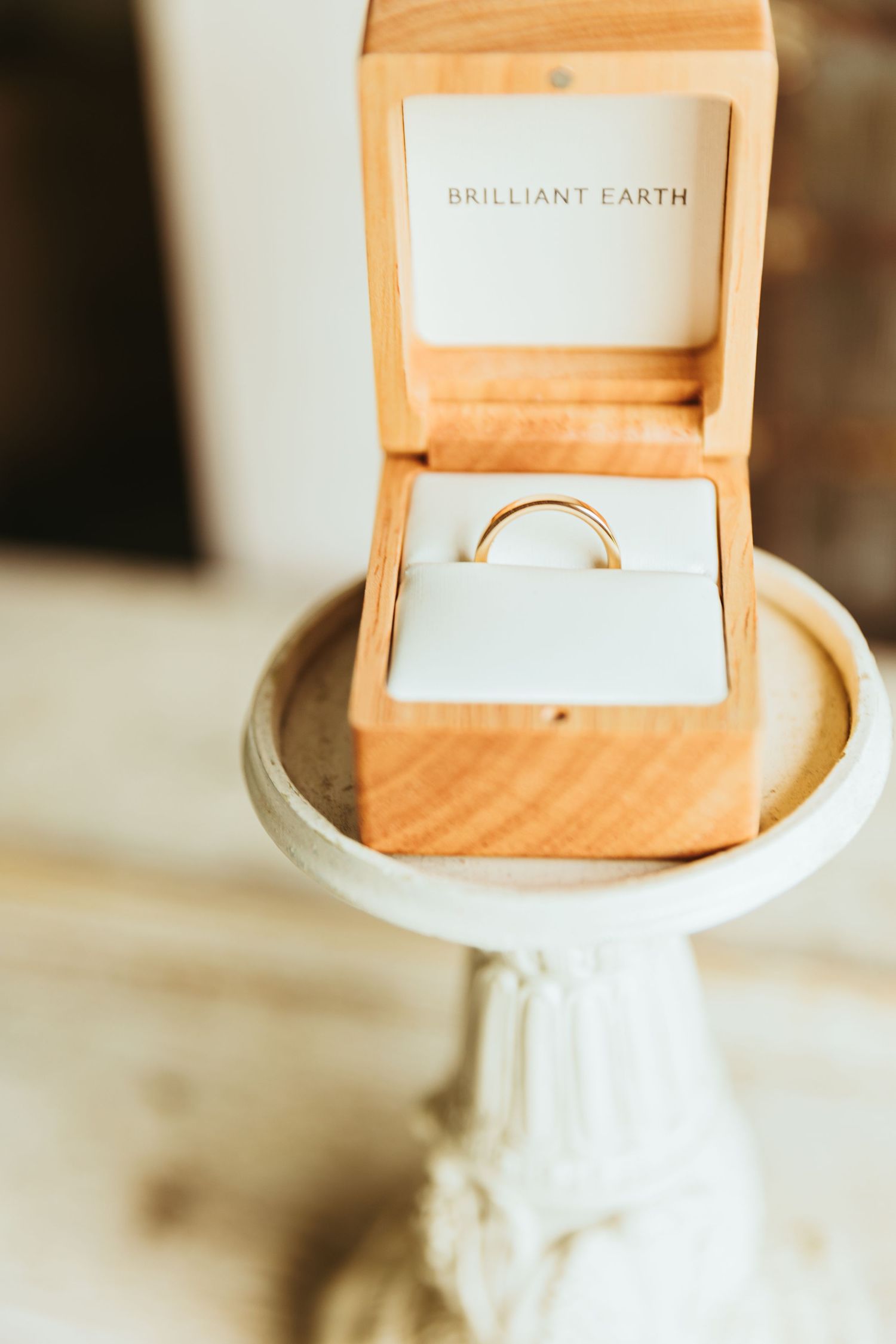 A close-up macro shot of a white ceramic vase or pottery piece showing intricate textural details and a wedding band
