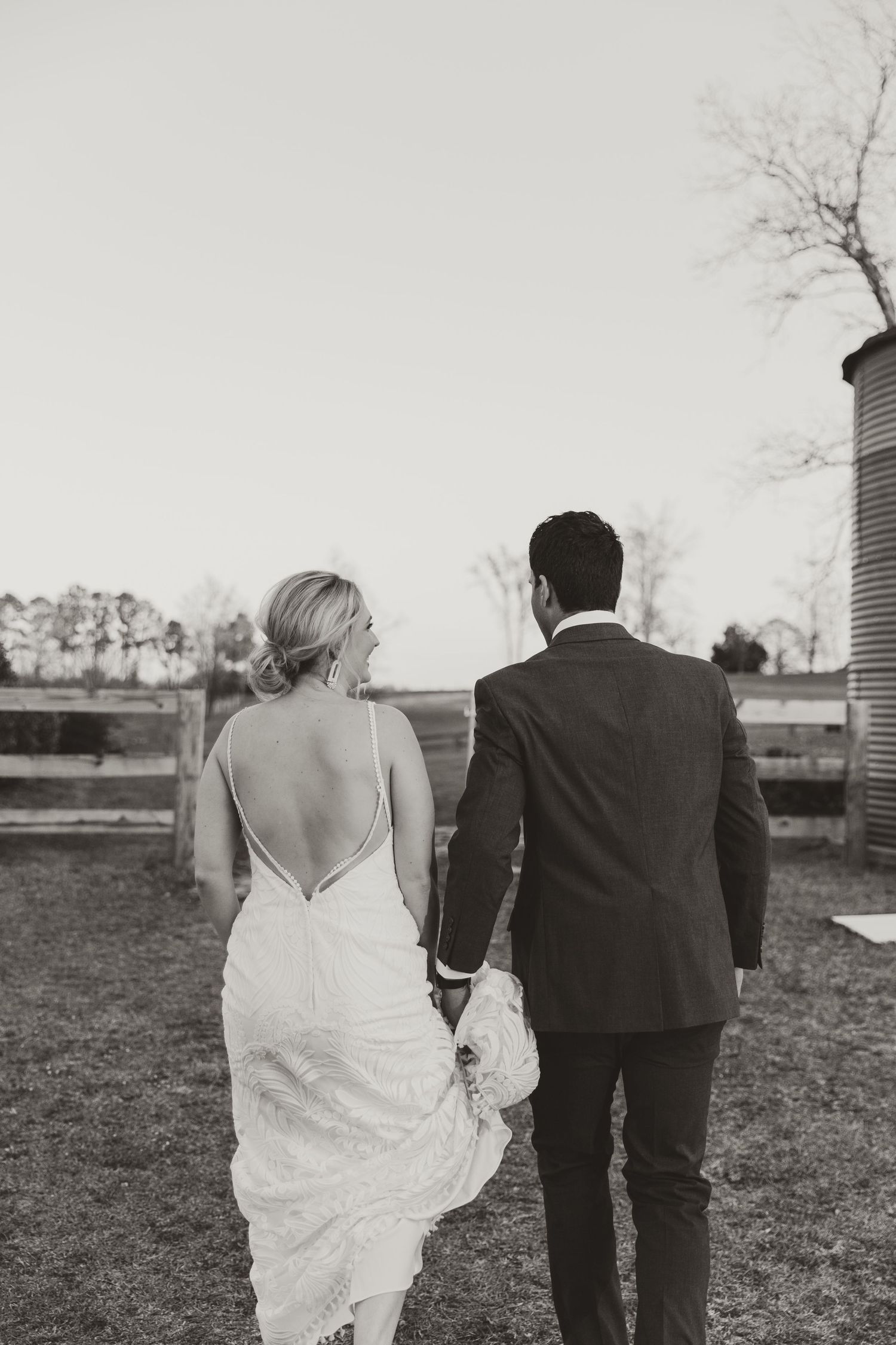 Black and white wedding photo showing couple and wedding party walking across an open field.