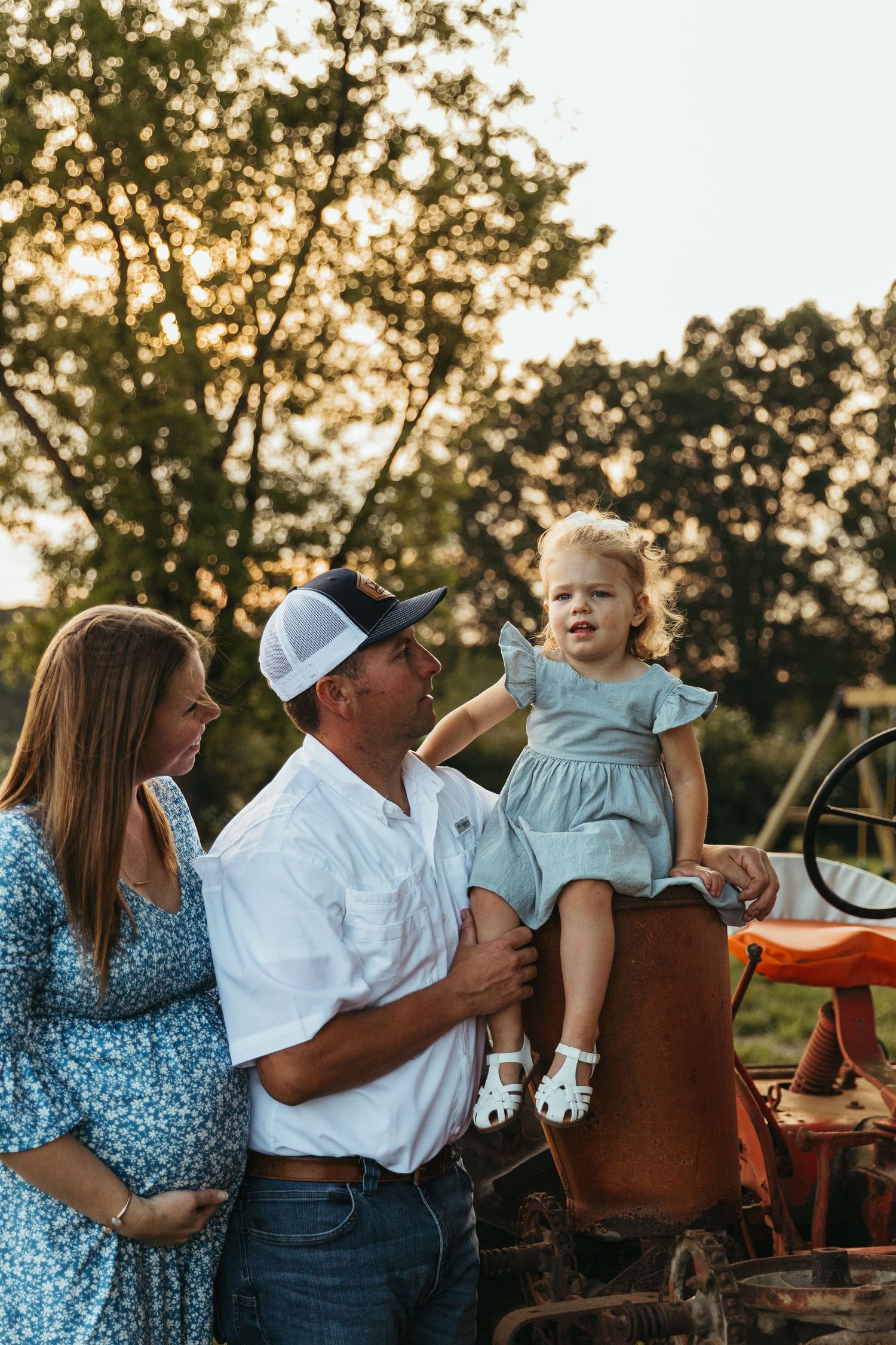 A family shares tender moments together during a golden sunset photo session on a farm.