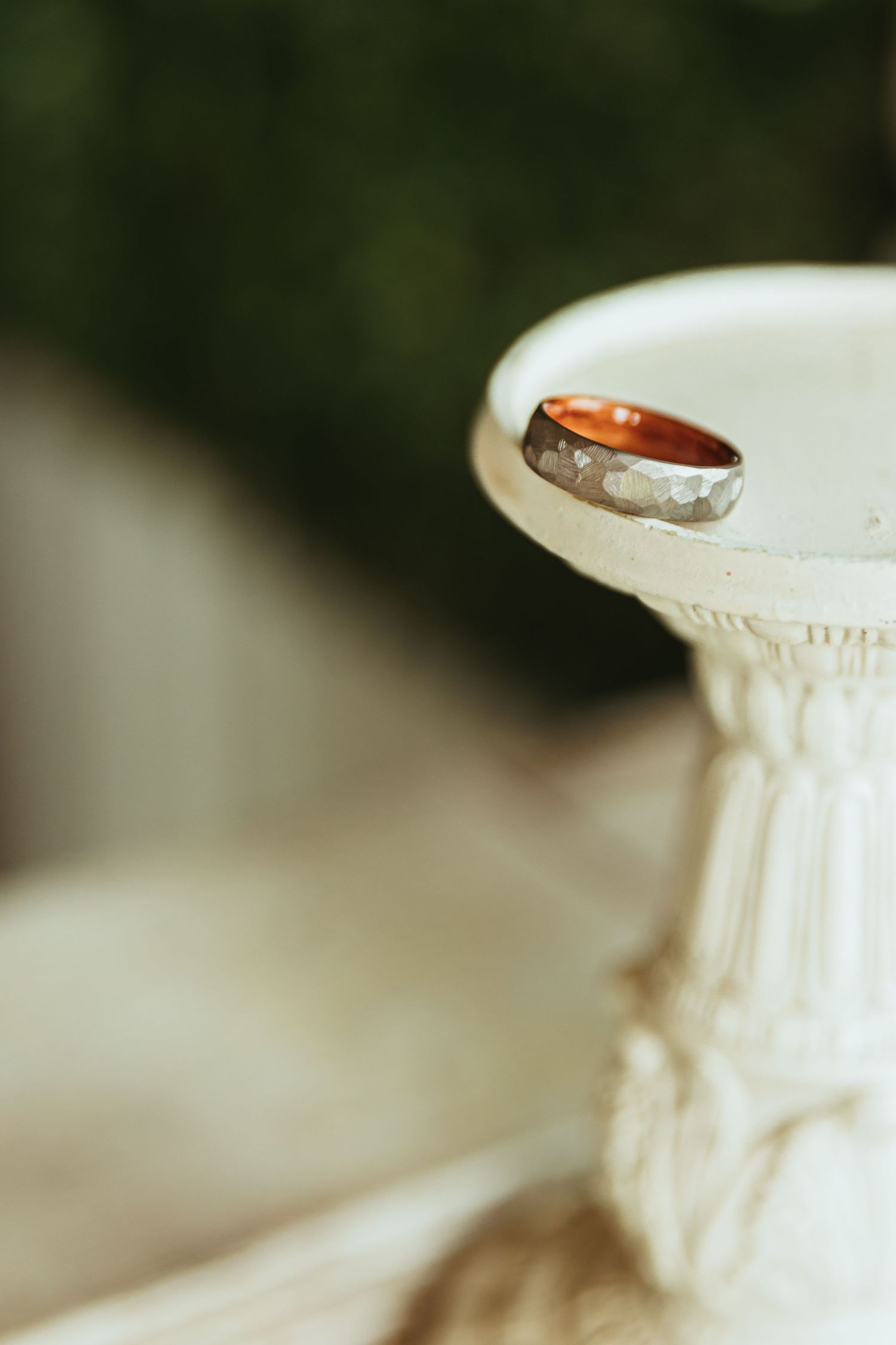 A close-up macro shot of a white ceramic vase or pottery piece showing intricate textural details and a wedding band
