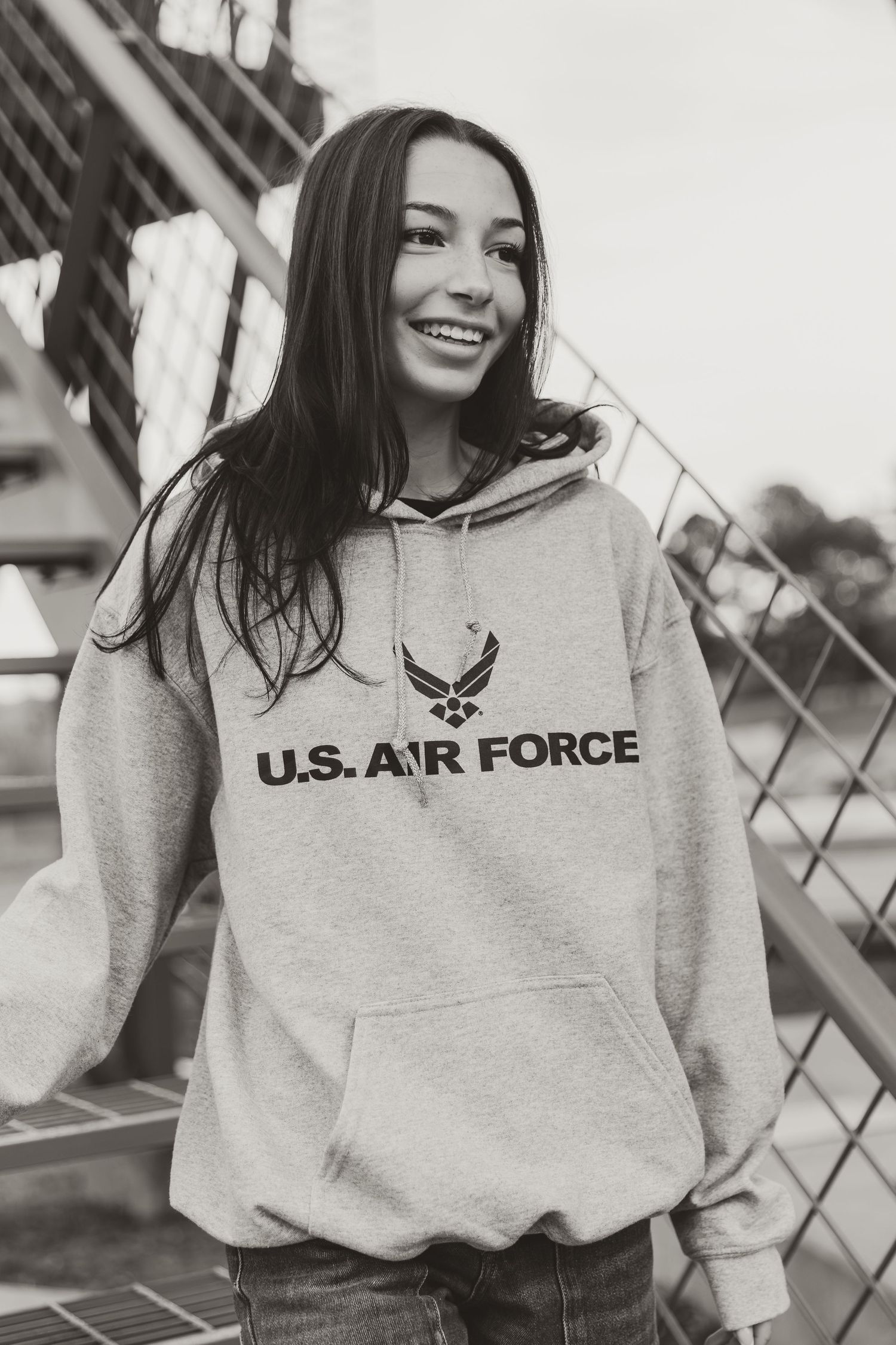 A series of black and white photos showing someone wearing a U.S. Air Force sweatshirt while smiling outdoors.