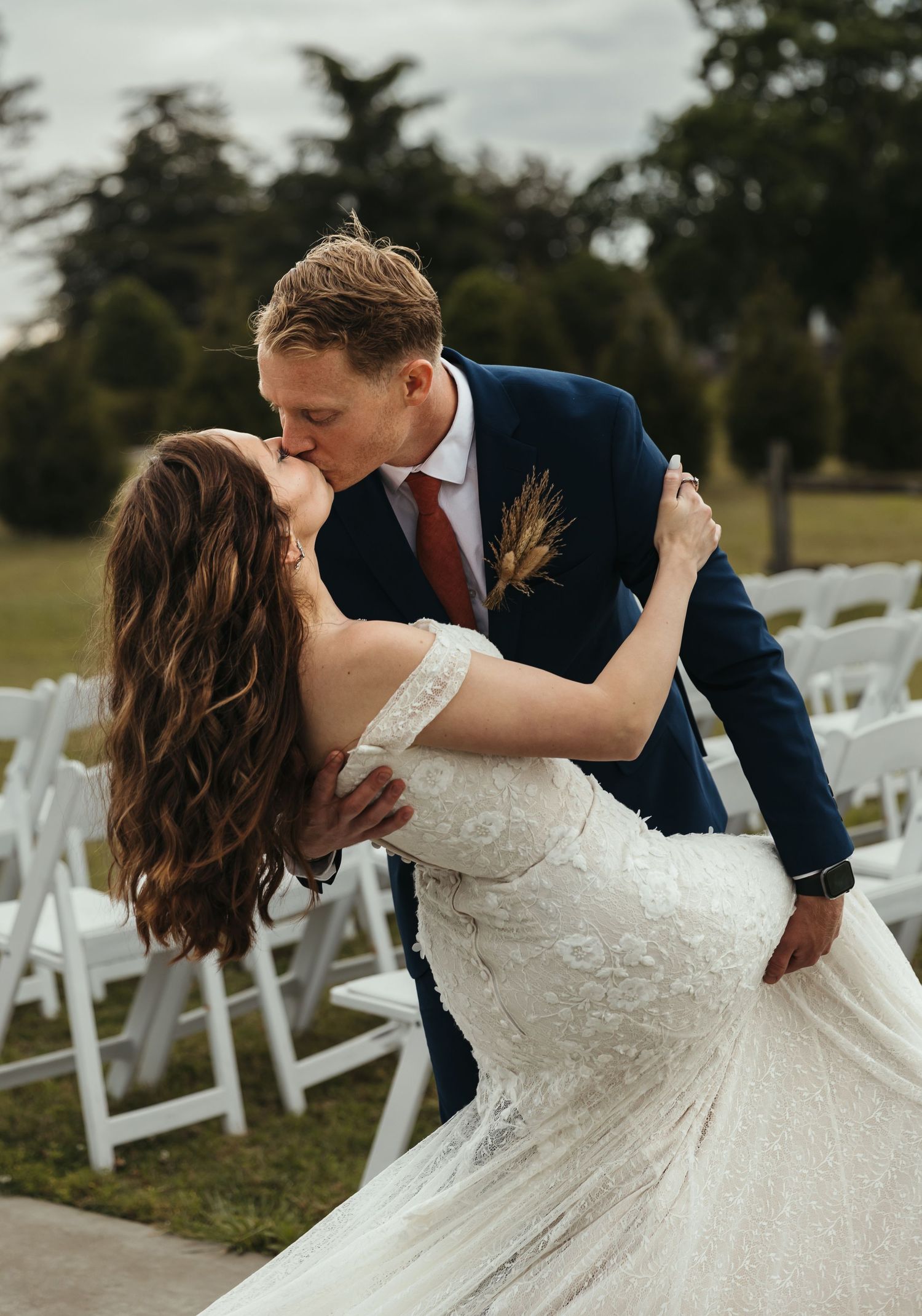 A romantic dip kiss sequence at an outdoor wedding ceremony with white chairs in the background.