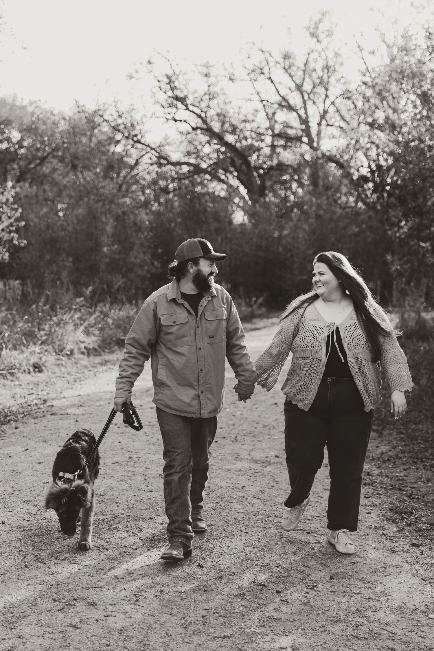 A couple walks along a dirt path with their German Shepard  in this vintage black and white photograph series.
