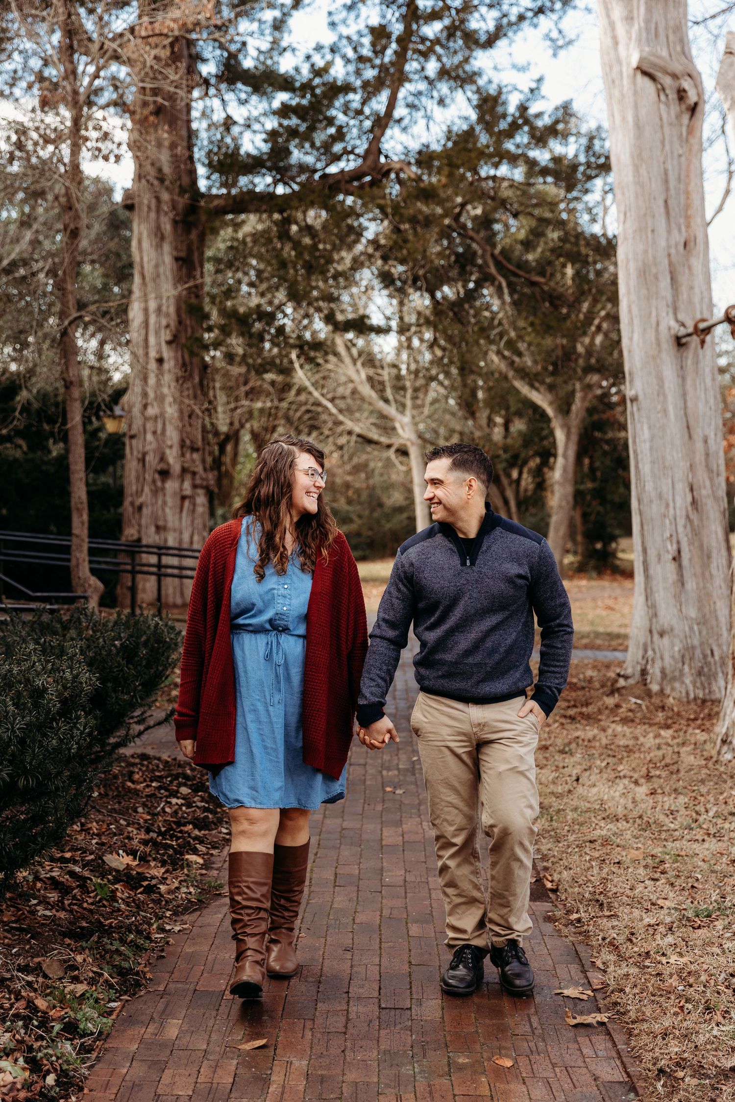 Couple walking and holding hands while looking at each other and smiling.