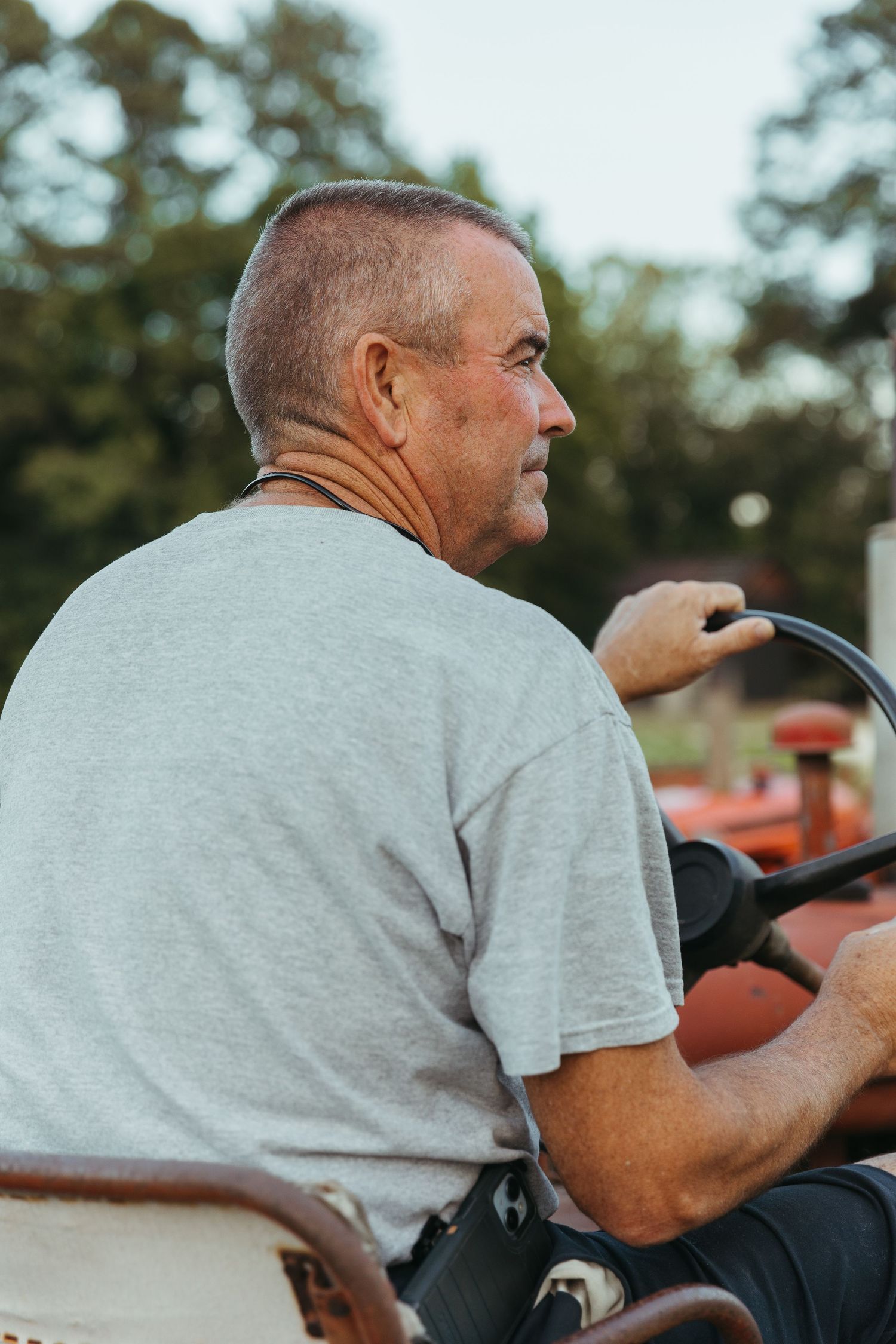 A person in a gray t-shirt sits on a vintage red tractor