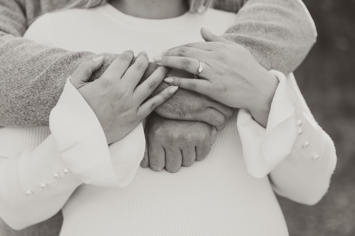 Couple with arms wrapped around each other showing off engagement rings
