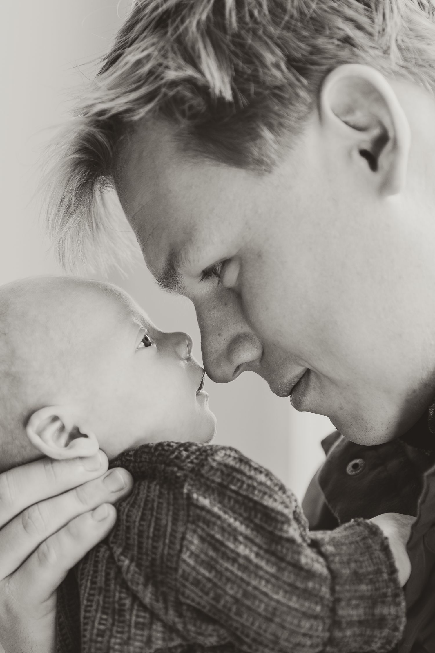 Black and white photo series showing a person in a knit sweater leaning in close to a Newborn baby.