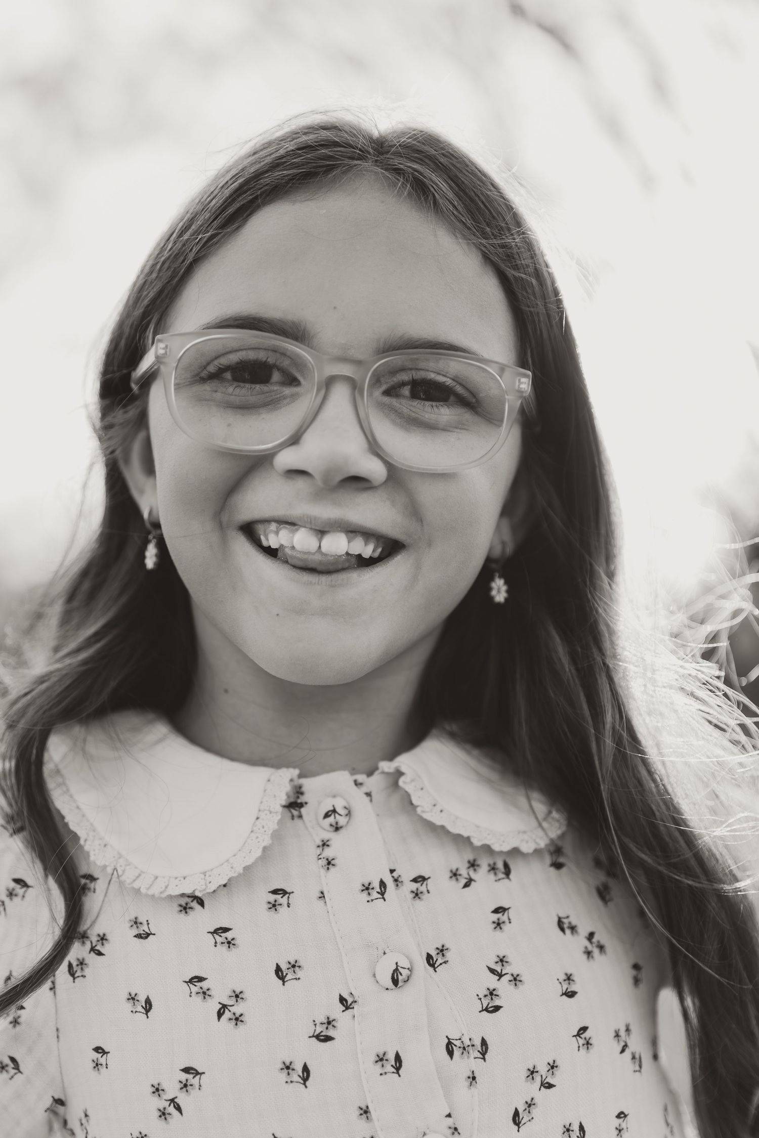 A series of four black and white photos showing someone wearing glasses and a patterned shirt with a joyful expression.