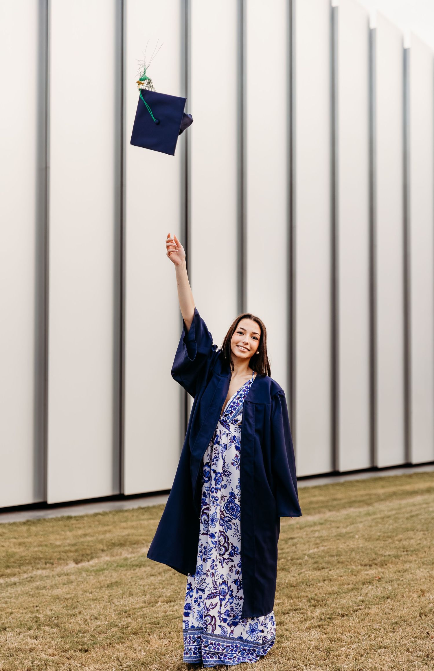 A graduate in a navy cap and gown poses joyfully on a lawn in front of a metal wall in a four-photo collage.