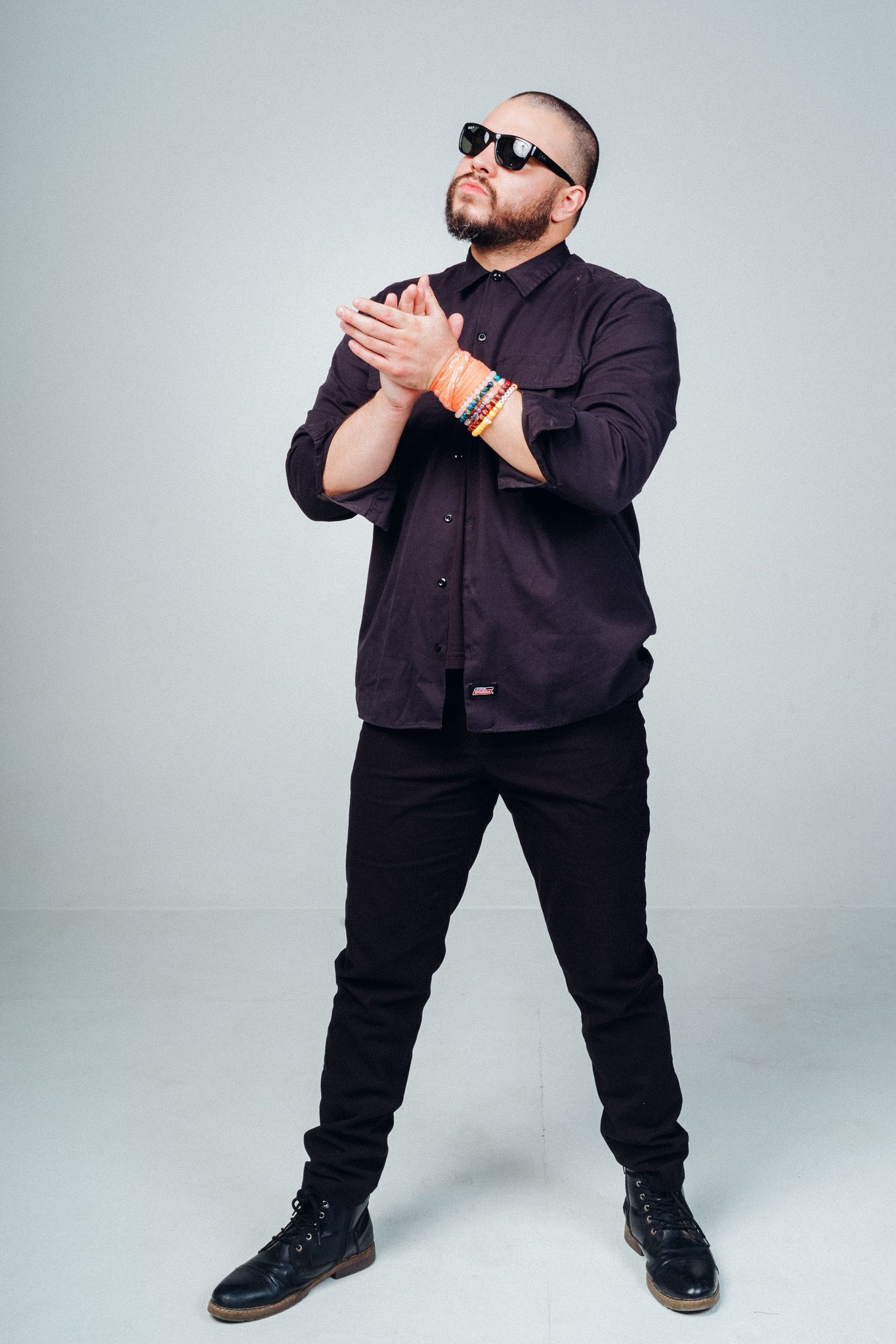 Person in black outfit striking different poses against light gray studio background.