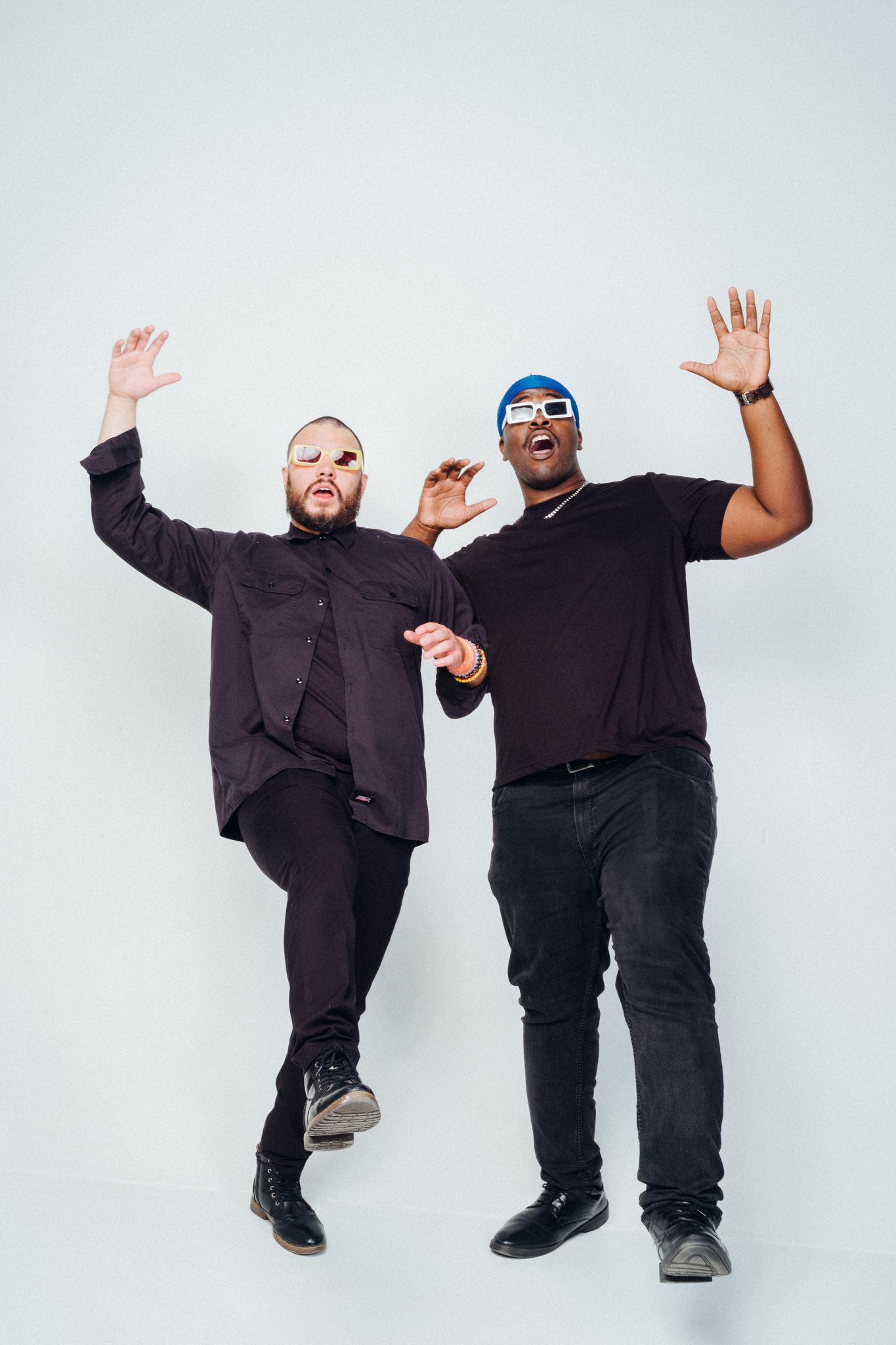 Two performers in dark clothing create dynamic poses against a white background in a four-part photo sequence.
