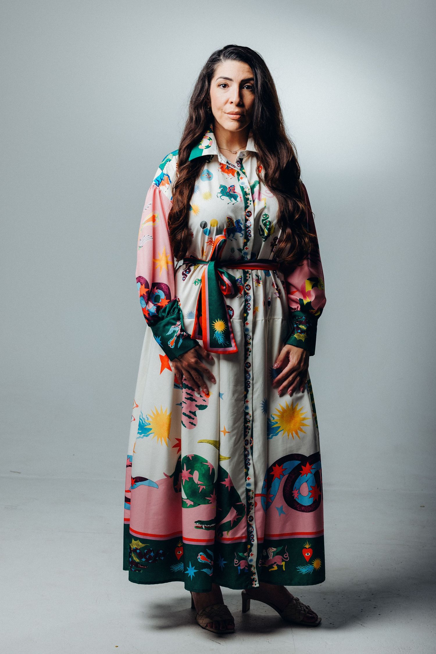 A person wearing a colorful floral print coat poses against a gray backdrop in a series of artistic fashion photos.