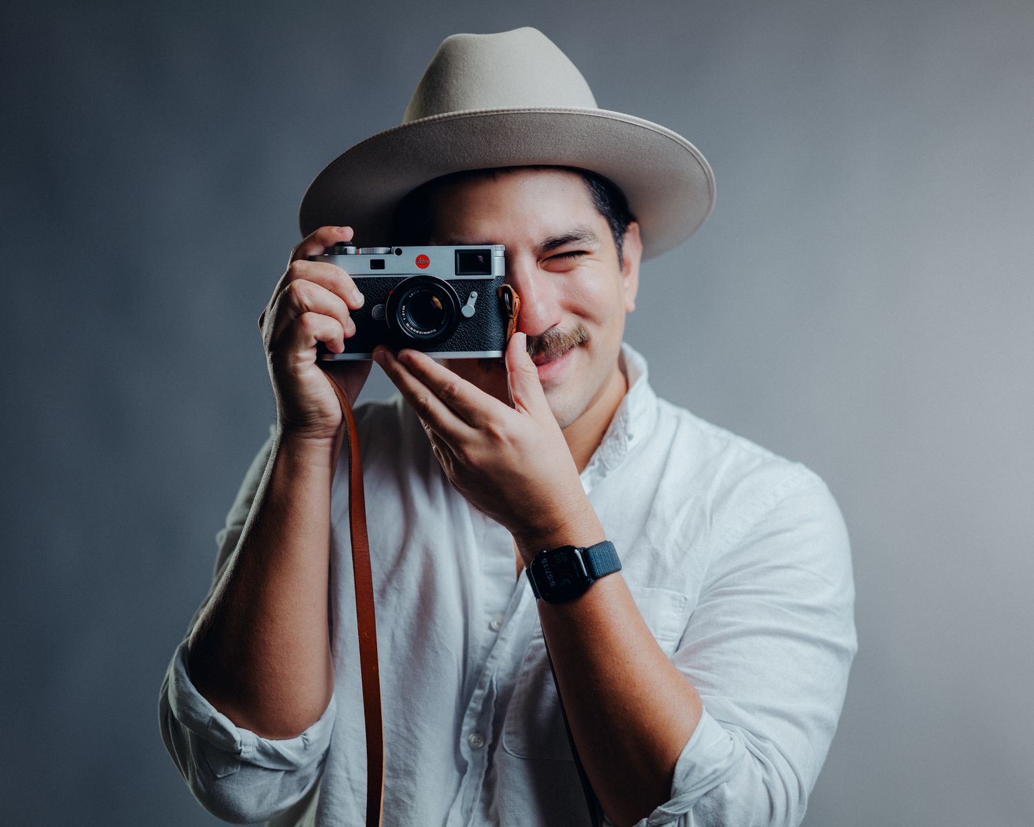 Series of shots showing a photographer using a vintage camera against a gray background.