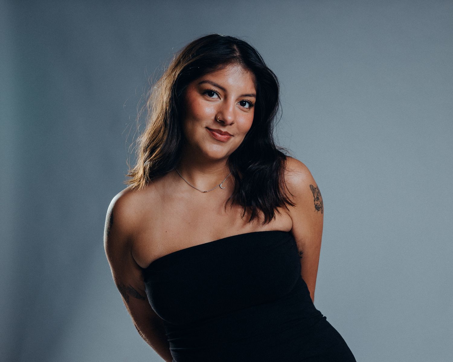 Professional studio portraits of a model in a black dress against a gray background.